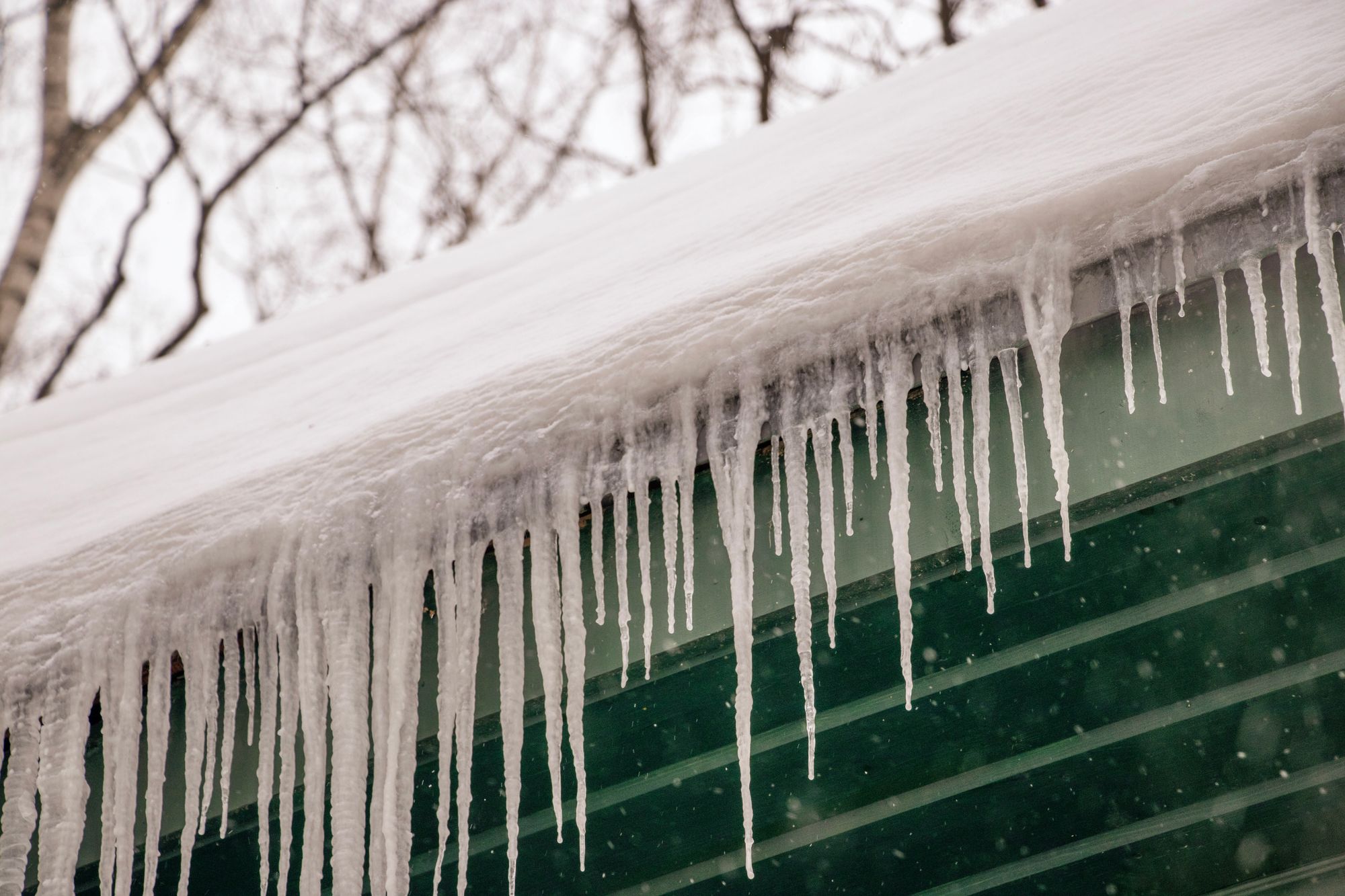 Icicles hanging from a snow-covered roof edge in winter